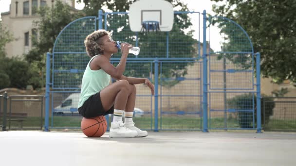 Femme afro-américaine fatiguée joueuse de basket-ball boire de l'eau après l'entraînement sportif — Video