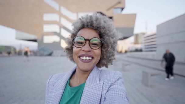 Neşeli Afro-Amerikan kadın kamerada konuşuyor, dışarıda yürüyor. Şehirdeki bir videoda siyah iş kadınının pov çekimi. — Stok video