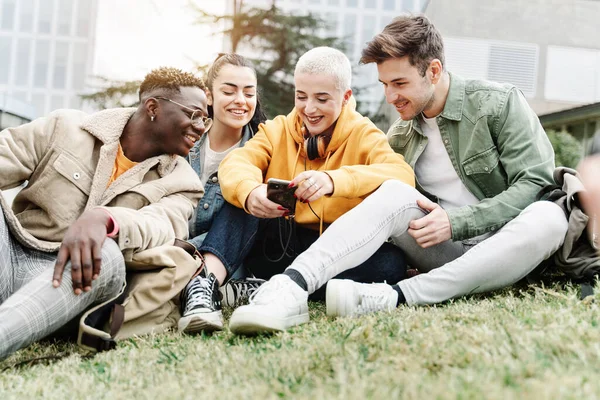 Gruppe av glade collegevenner som deler øyeblikk på mobilappen på universitetets universitetsgress – stockfoto