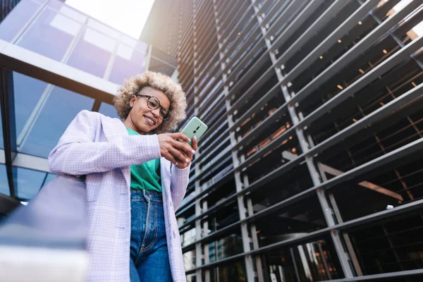 Trendy afroamerikansk profesjonell kvinne som bruker smarttelefon utenfor lederarbeidsplassen. Kreativ forretningskvinne som sender SMS-appen – stockfoto