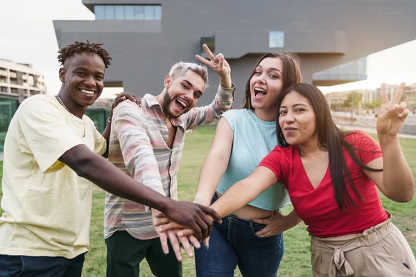 En gruppe internasjonale venner som stabler hender utendørs - glade unge mennesker som har det gøy sammen og feirer sammen – stockfoto
