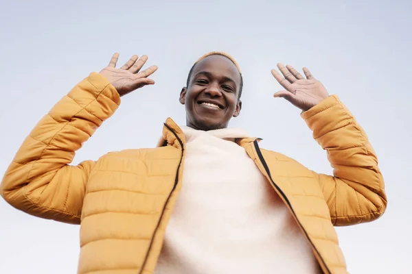 Porträt eines aufgeregten afroamerikanischen Mannes mit freundlicher Geste erhobener Arme, die in die Kamera blicken — Stockfoto