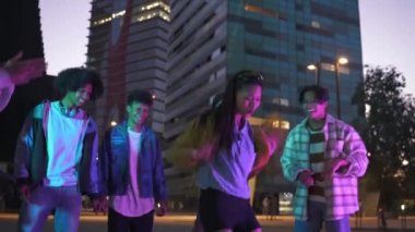 Genç Asyalı Çinli kız, şehirdeki müzik sokak partisinde Z jenerasyonu arkadaşlarıyla dans ederek eğleniyor.