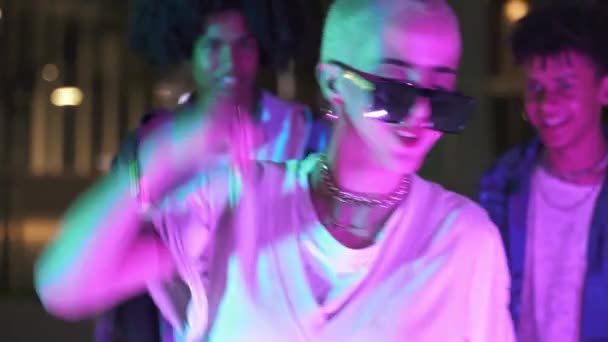 Молодая модная женщина с выбритыми светлыми волосами танцует с друзьями на уличной вечеринке, веселясь на сумасшедшем празднике — стоковое видео