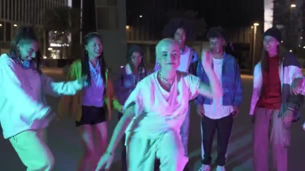 Zabawna młoda kobieta z ogolonymi włosami tańcząca z wielorasowymi nastolatkami na imprezie ulicznej zabawiająca się razem — Wideo stockowe