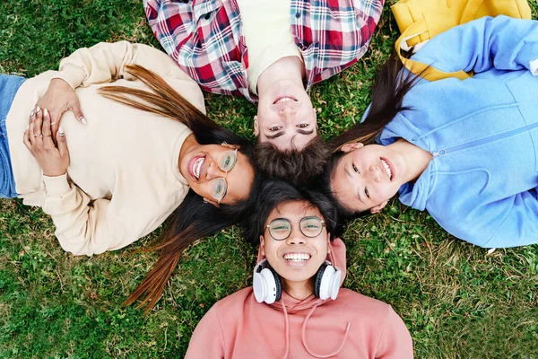 Avoir du bon temps avec des amis - Vue du dessus d'un groupe de jeunes étudiants universitaires couchés sur l'herbe leur. — Photo