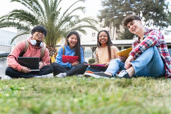 College student friends sitting in the campus park looking to camera - Diversity in University Education — kuvapankkivalokuva