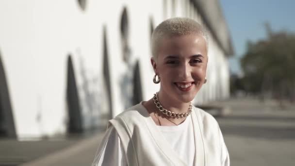 Retrato de jovem mulher moderna com cabelo loiro raspado sorrindo e olhando para a câmera com emoção positiva desfrutando de estilo de vida bem sucedido — Vídeo de Stock