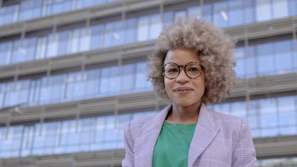 Portrait of Professional African American business woman with blond hair and modern eyeglasses in the financial city looking to camera with positive smile — Αρχείο Βίντεο
