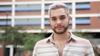 Kendine güvenen, modaya uygun giyinmiş, kameraya bakan genç bir adamın portresi. Yüzünde göz makyajı olan yakışıklı bir gay. Cinsiyet değişimi, lgbt ve çeşitlilik kavramı 