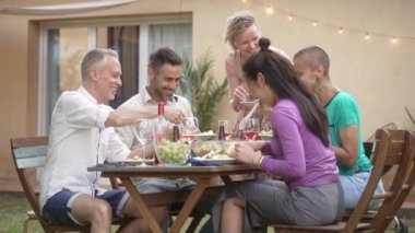 Mutlu arkadaşlar ev bahçesinde sağlıklı bir akşam yemeği yerken eğleniyorlar - arkadaşlık, yemek, toplanma ve yaz yaşam tarzı 