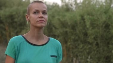 Doğa ormanında dikilen, temiz hava soluyan, alacakaranlıkta doğayı düşünen kadın portresi. Tıraşlı saçlı bir kadın parkta sakin ve sakin bir hayatın tadını çıkarır. Güçlendirme ve Memnuniyet 