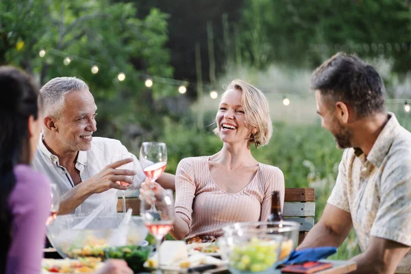 Mature Friends Having Dinner Table Garden Summer Evening Drinking Wine — kuvapankkivalokuva