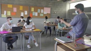 Secondary school students and teacher wearing medical face masks writing notes during class at the High School or College. Back to School in Covid Pandemic