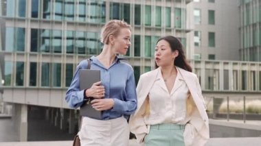 Stylish Business women walking and talking outdoors the workplace, Caucasian and Asian female successful coworkers in the financial city