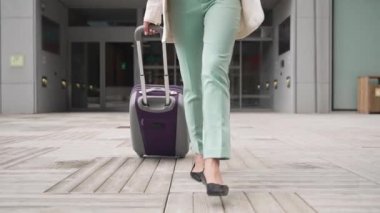 Young Asian Professional Woman walking outside the office carrying suitcase going to the airport after the business trip - Female inspiration and ambition