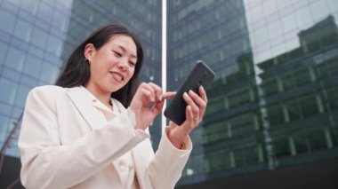 Young Asian Elegant Professional Business Woman using cell phone to text outside the office - Female inspiration and ambition