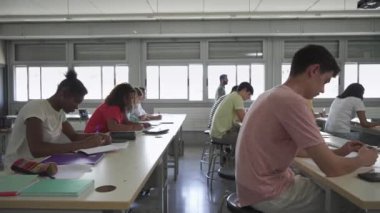 Teacher walks in the classroom explaining Lesson to class of Teenager students Learning at High School College