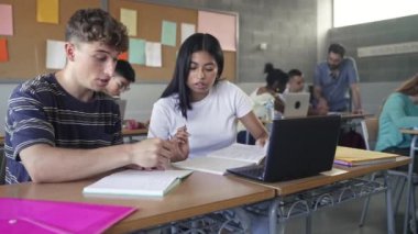 Teenager classmates friends doing exercise and working together in the Secondary School Classroom - Multi ethnic caucasian and Latin American students