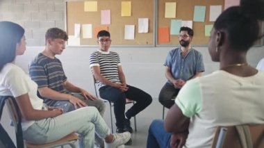 Genç liseli öğrenciler yüksek öğrenimde genç erkek öğretmenlerin grup destek konuşmalarını dinliyor ve dinliyorlar