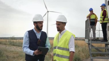 Rüzgar türbini elektrik çiftliğinde çalışan mühendis ve elektrik teknisyenlerinden oluşan profesyonel ekip yenilenebilir yeşil enerji projesi planlıyorlar.