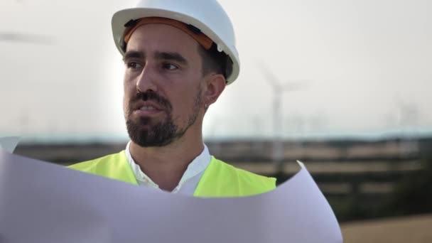 風力タービン発電所で働く青写真マップを検査安全ヘルメットを持つ男性エンジニアの労働者 — ストック動画