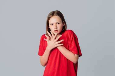 Şok olmuş ve endişeli esmer kız soluk soluğa, kameraya bakıyor, tanık felaketi, gri arka planda duruyor. Genç duygusal kadın.