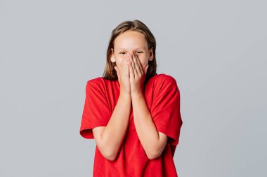 Oh my gosh. Portrait of surprised cute brunette teen girl gasping in awe, react shocked, covering mouth with hands, wear in casual red t shirt, standing over gray background. Young emotional woman clipart