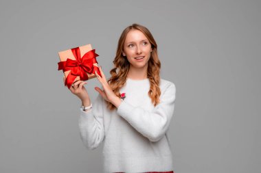 Tahmin et içinde ne var. Çekici sarışın bir kadının portresi hediye kutusundaki tıkırtıları dinliyor. Meraklı kız hediye kutusunu sallıyor ve uzaklara bakıyor, düşünüyor. Gri arkaplan üzerinde izole