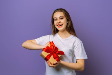 Hediye kutusu olan mutlu esmer kadın. Mor arka planda çekici esmer kız fotoğrafı.