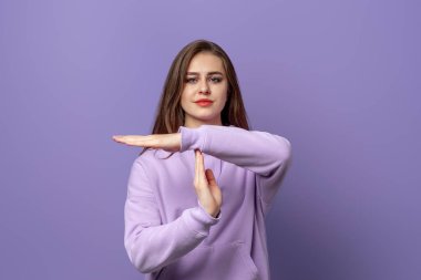 Ciddi, esmer bir kadın. Mor arka planda duran mor bir kapüşonlu giyiyor. Uyarı kavramı, yasaklama