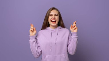Hevesli genç kadın umut dolu, umut dolu, umut dolu, amacına ulaşmak isteyen, mor arka planda modaya uygun kapüşonluyla duran