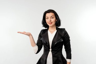 Siyah resmi ceketli güzel iş kadını beyaz gömlekli mutlu görünüyor ve beyaz arka planda duran ürününüzü sunuyor. İş konsepti