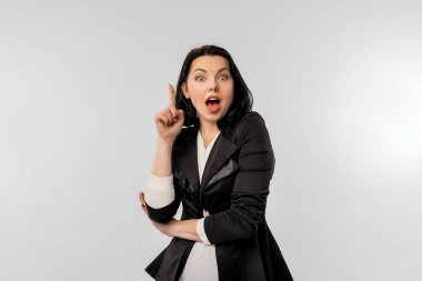 Siyah saçlı bir iş kadını kameraya bakıyor ve bir fikri var. Kariyer kızı parmak kaldırıyor. Eureka jesti. Küçük işletme sahipleri, kadın girişimciler konsepti