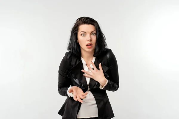 Siyah resmi ceket giyen genç bir iş kadını beyaz gömlekli, korkmuş ve şok olmuş bir ifade, korku ve heyecanlı bir yüz ifadesi.