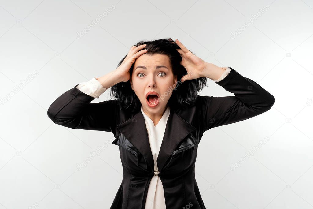 Shocked businesswoman in black formal jacket white shirt grabbing to head. Portrait of surprised young businesswoman looking at camera and keeping his mouth open while isolated on white