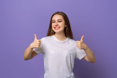 Mutlu gülümseyen, güzel, esmer kadın, mor arka planda duran, baş parmak işareti yapıyor. Pozitif duygu kavramı
