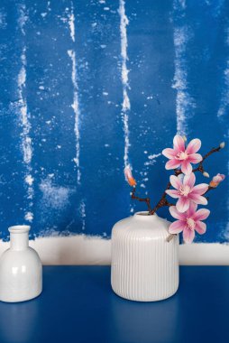 Mavi duvara karşı seramik vazoda parlak beyaz-pembe bir buket. Seçici odaklanma. Mesaj için yer. Ev dekorasyonu kavramı