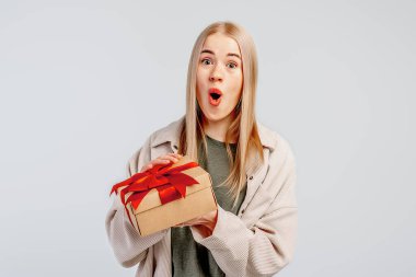 Hediye kutusunu açan heyecanlı genç bir kadın görüntüsü. - Evet. Güzel kız gülümsüyor ve arka planda hediye kutusuyla poz veriyor. Yeni yıl kadınlarının doğum günü konsepti