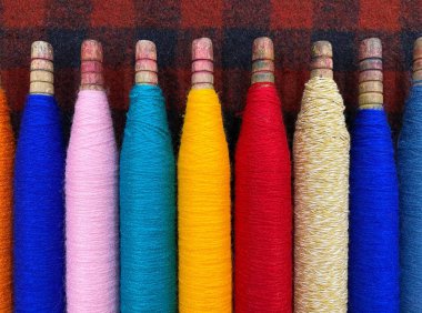 Renkli iplikler. İplik. İplikli bobinler. Kumaş. Dikiş iplikleri. İplik kabuğu. Spoolllardaki renkli ipliğin dokusu.