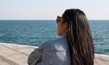 Asian young lady sittinf and enjoying the sea view. Amazing view of sea