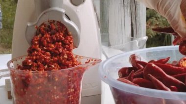 Kadın öğütücüde acı biberi öğütüp püre çeviriyor. Acı sos üretimi