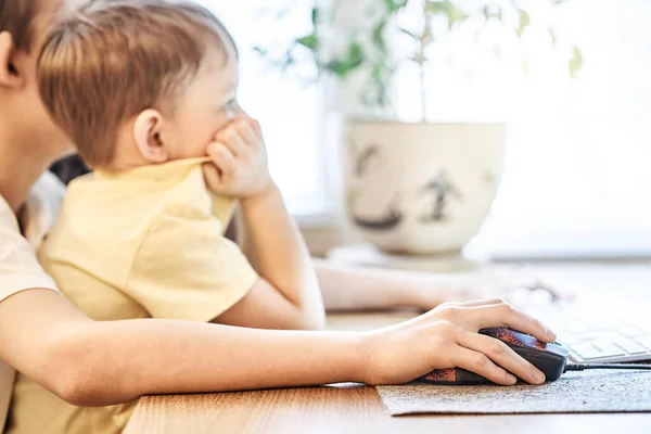 Sarı Tişörtlü Konsantre Küçük Çocuk Bilgisayara Bakıyor Kardeş Dizlerinin Üzerinde — Stok fotoğraf