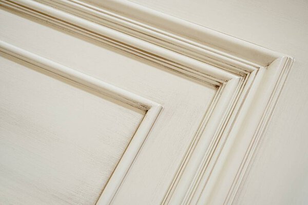 Furniture beige facade panel with moldings and brown patina in classical style extreme closeup