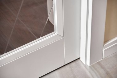 Cam yüzeyinde eşkenar dörtgen desenli şık iç kapılar ve yenilenmiş dairenin ışıklı ferah odasındaki gümüş saplar.