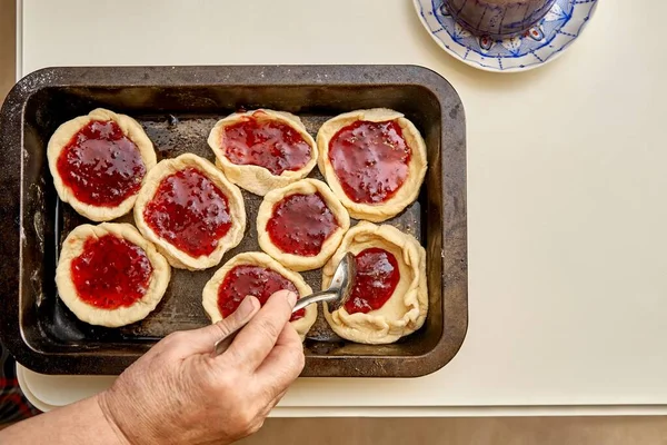 老妇人在厨房里的白桌上用天然自制的浆果果酱做甜点填饱了生馅饼 — 图库照片