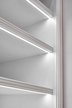 Boş raflı beyaz gardırop bölümü ve lüks apartman dairesinin geniş gömme dolabındaki raflarda aydınlatma.