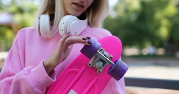 Junge blonde Frau spielt mit Penny-Board-Rädern im Park — Stockvideo