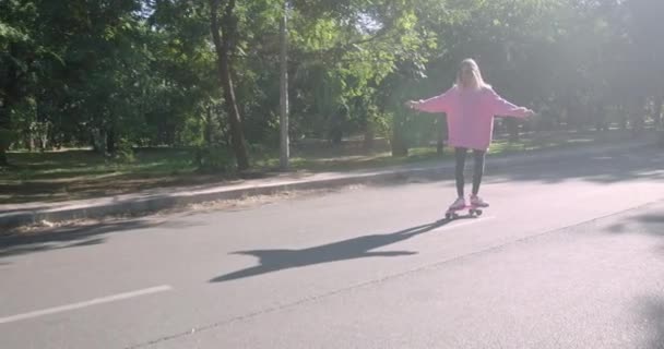 ブロンド女性は公園でペニーボード上でスケートを学ぶ — ストック動画