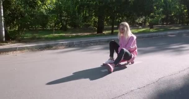 若い女性は公園道路斜面に乗ってペニーボードに座っています — ストック動画